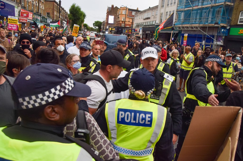 Police officers move a right-wing protester who was arguing with the crowd gathered for a rally against the far right and racism in Finchley after a week of far-right riots across the UK